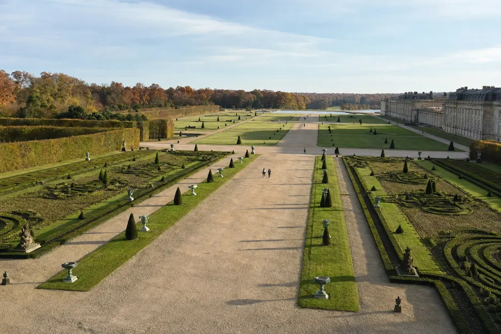 Ampio giardino barocco con viali rettilinei e prati geometrici visto dall'alto nel pomeriggio (immagine creata con AI)